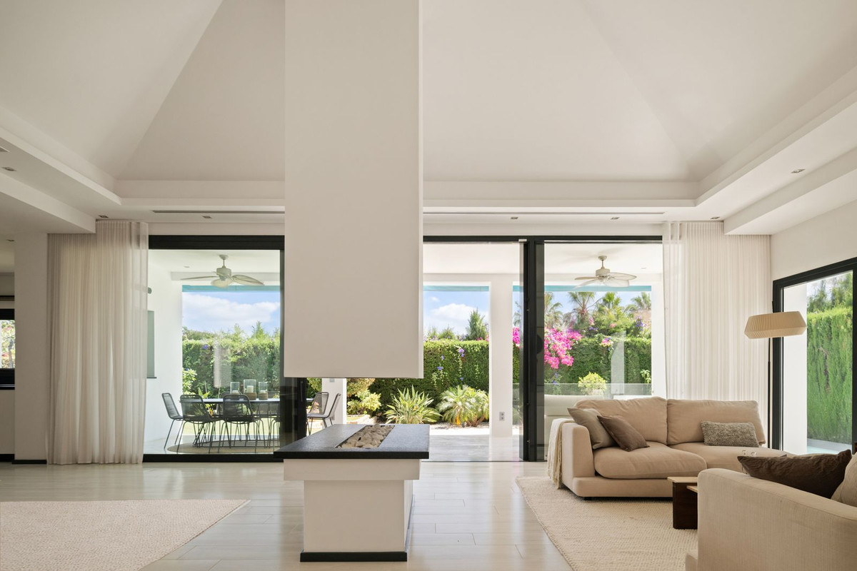 Living room with double-sided fireplace, high ceiling and open glass doors to the terrace