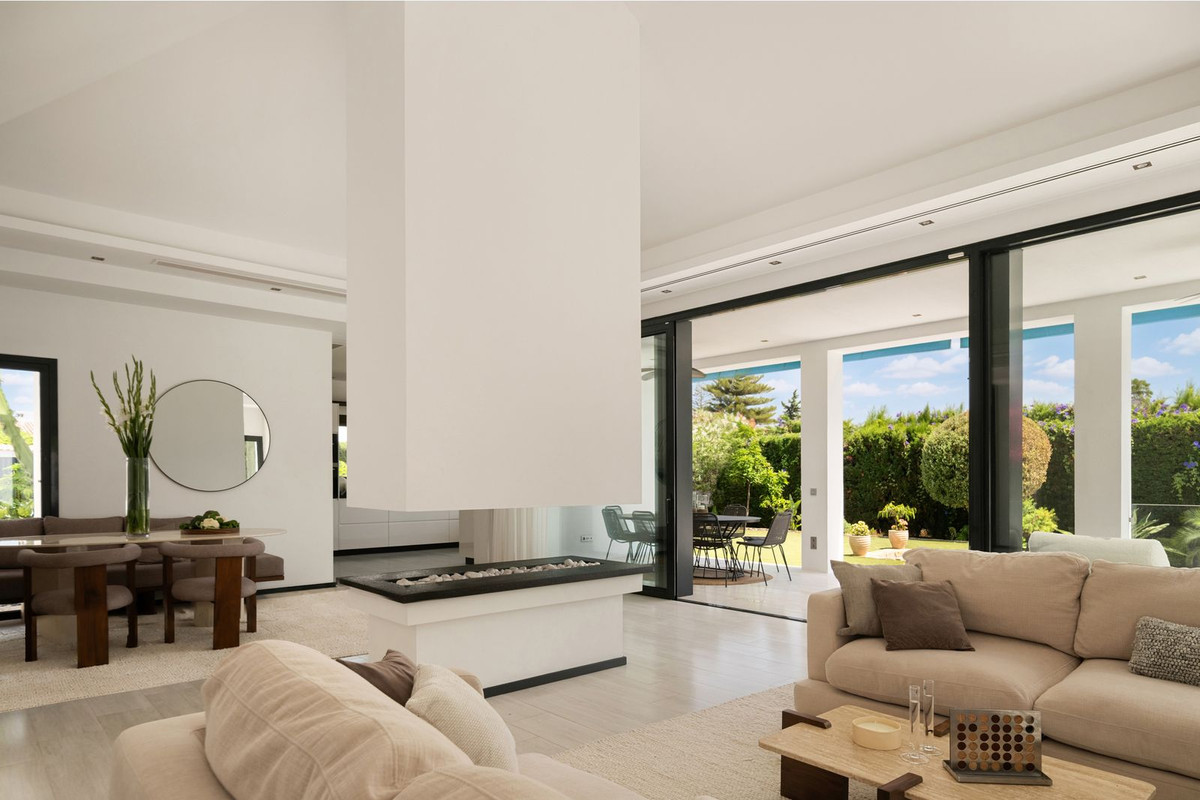 Fireplace between living and dining areas with fully open sliding doors to the garden