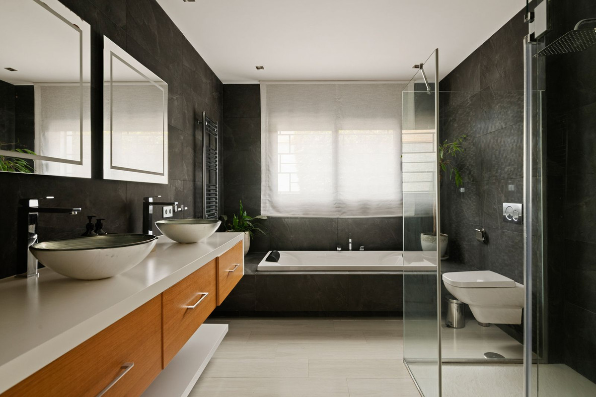 Bathroom in dark slate with twin basins, built-in bath and glass shower