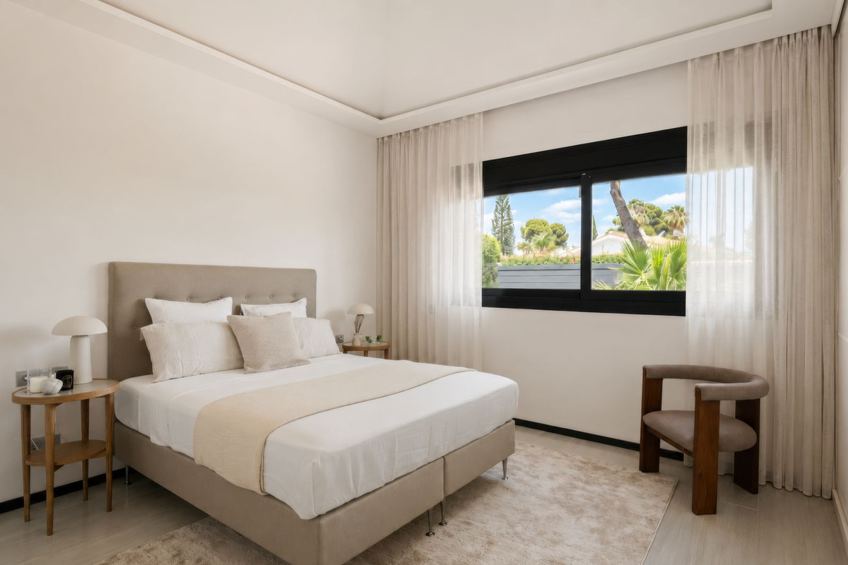Bedroom with view of palms and cypresses through black-framed windows